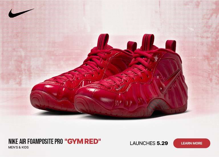 A digital marketing banner features a pair of all-red Nike Air Foamposite Pro Gym Red sneakers set against a white and red halftone dot gradient background. The Nike swoosh logo is in the top left corner, while text on the left reads LAUNCHES 5.29. The right side displays text reading NIKE AIR FOAMPOSITE PRO GYM RED MEN'S & KIDS above a red LEARN MORE button.